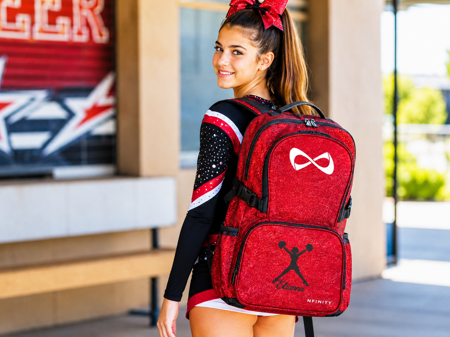 Teenage cheerleader wearing a personalized red glitter cheer backpack with custom embroidery and sparkle finish
