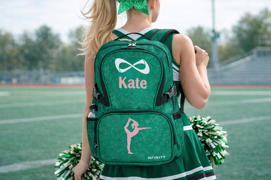Personalized green glitter cheer backpack with custom name Kate and cheerleader silhouette design on Nfinity bag worn by athlete on field
